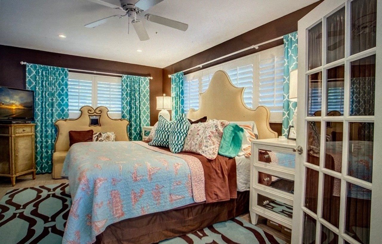 A bedroom with a king size bed and a ceiling fan.