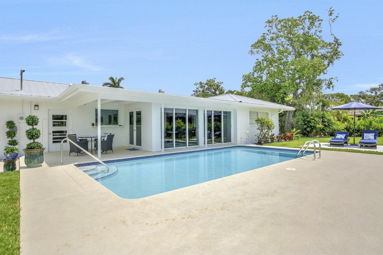 A white house with a large swimming pool in front of it