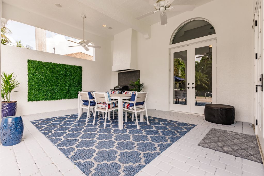 A patio with a table and chairs and a blue rug.
