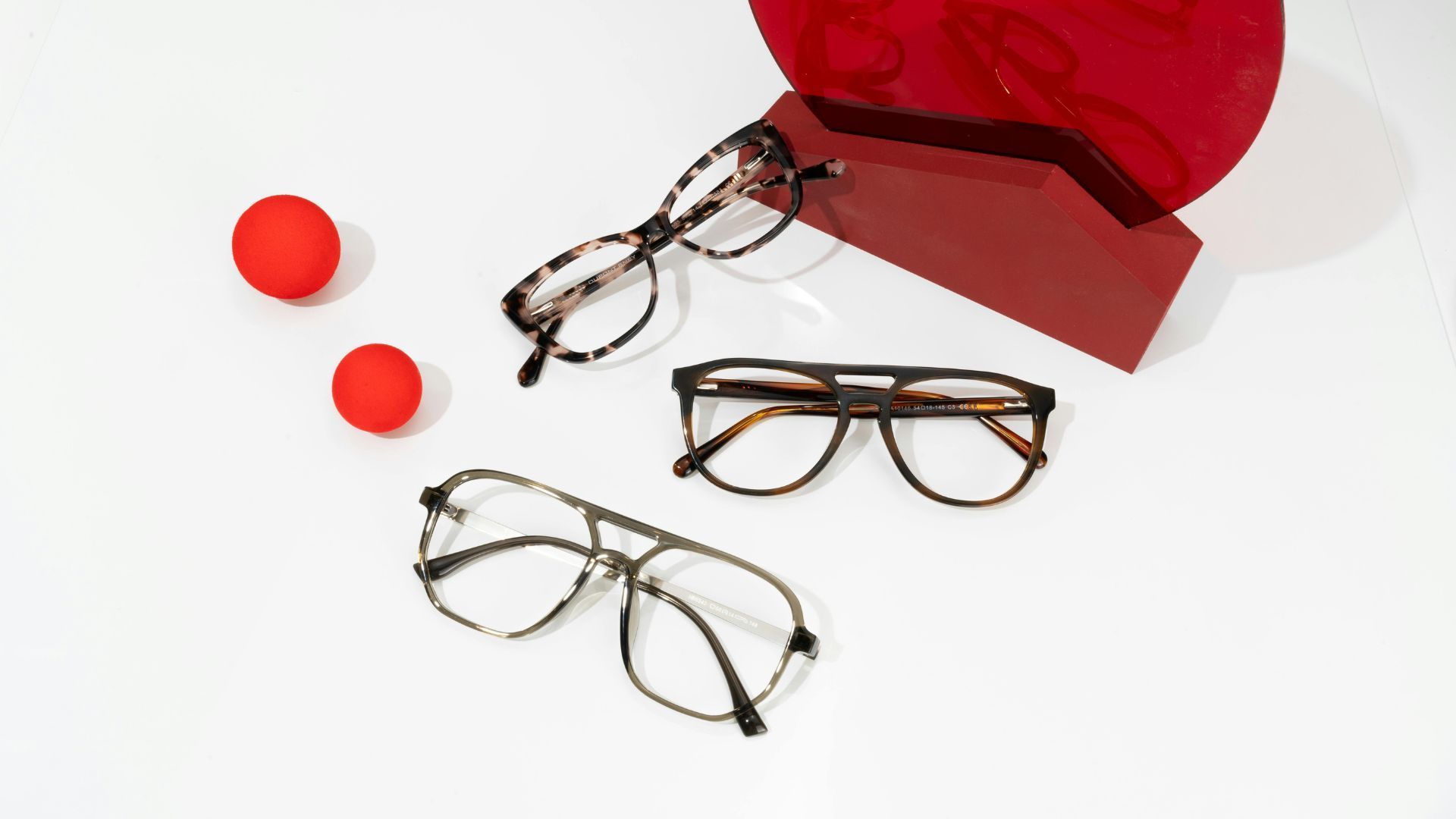 Three pairs of eyeglasses in tortoiseshell patterns displayed on a white surface with red accents.