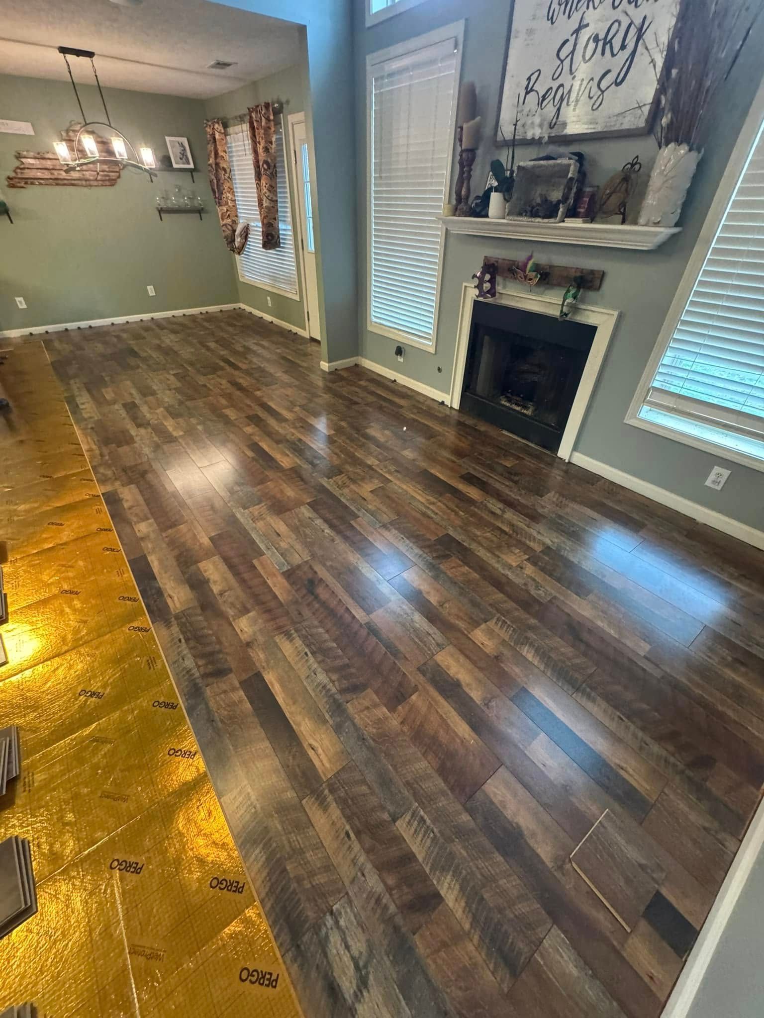 Hardwood floor installation in progress, showing new dark wood flooring and underlayment.