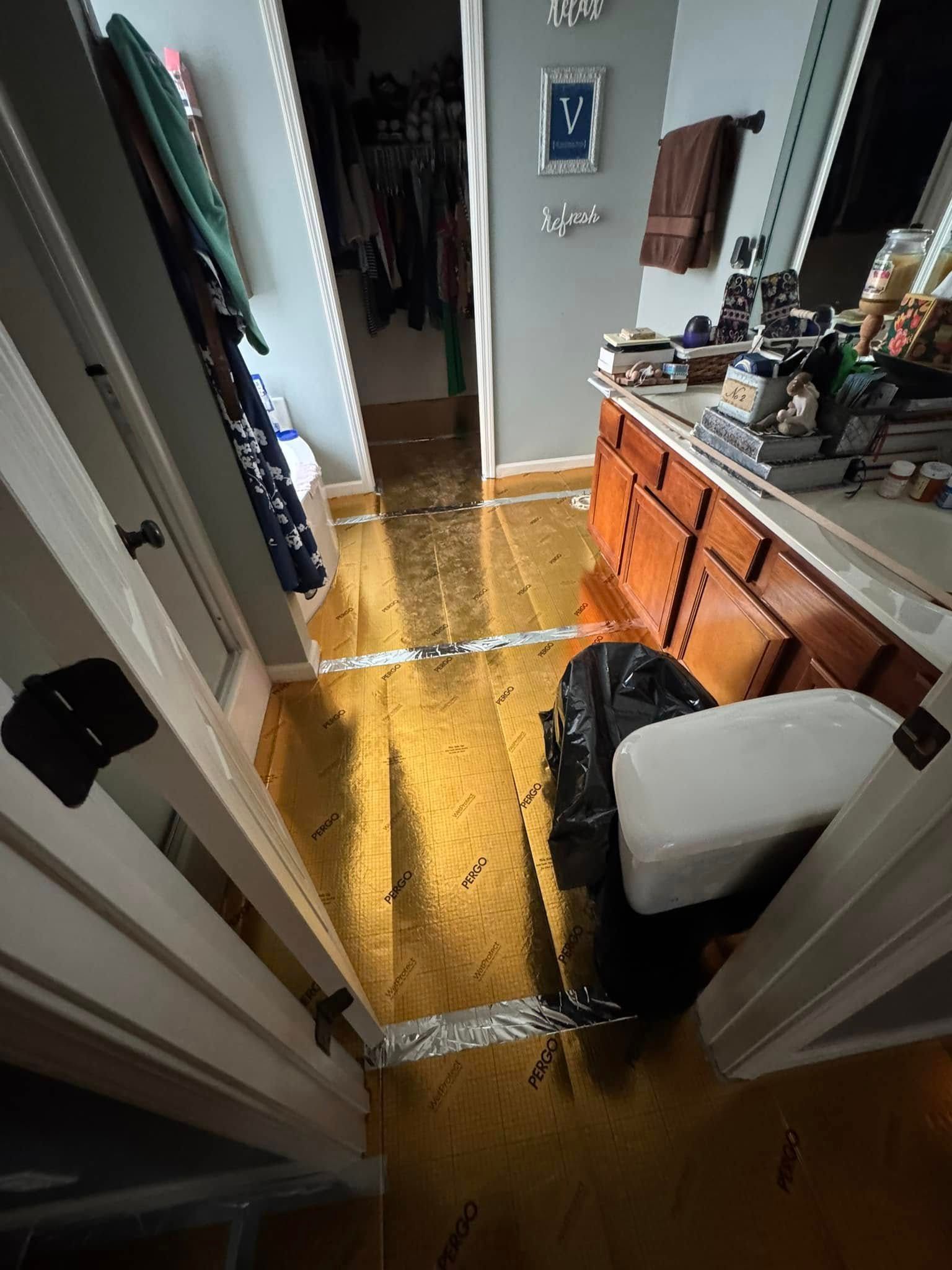 Water damage in bathroom and adjacent areas, visible puddles and flooded flooring, open doorways.