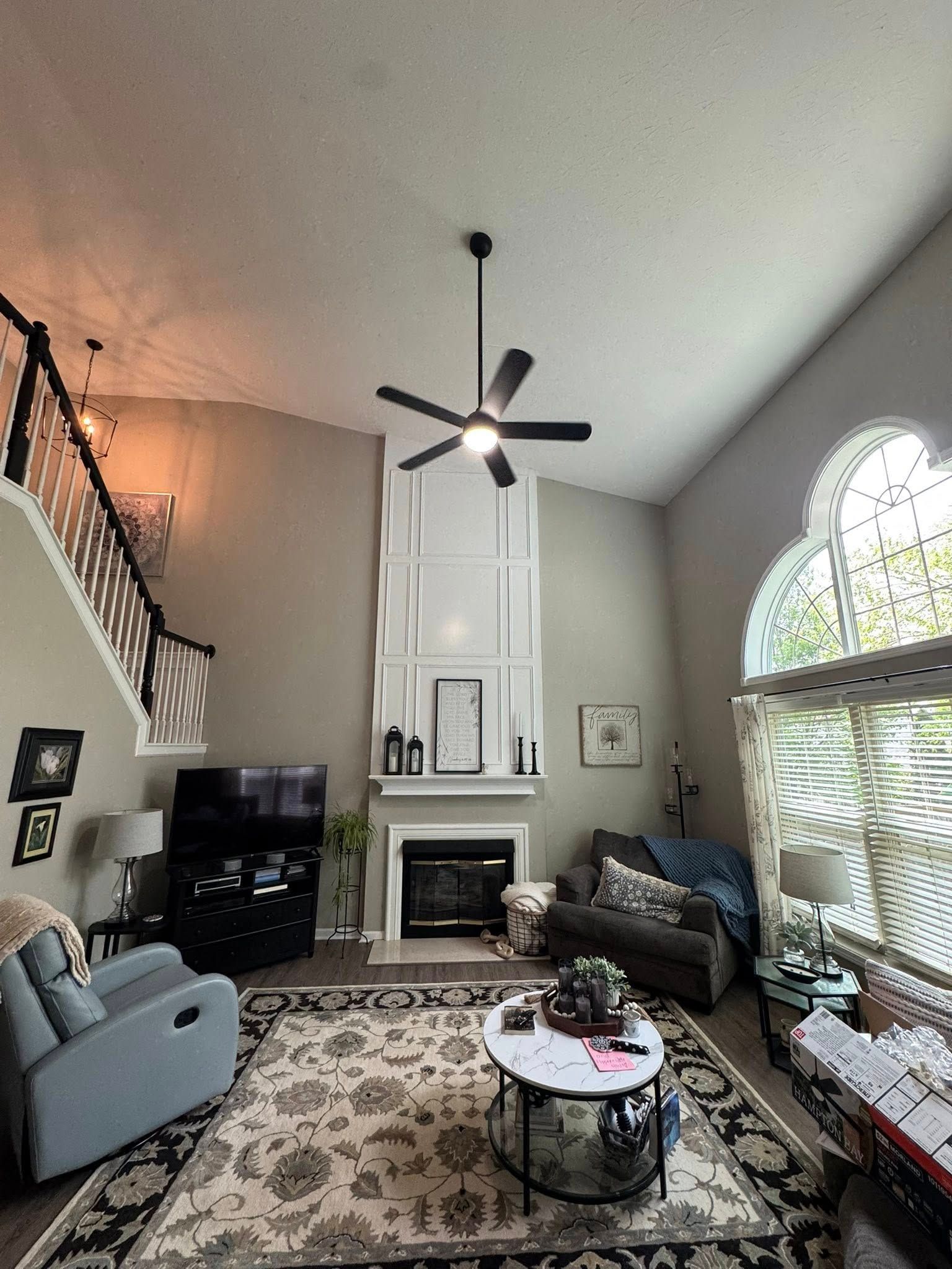 Living room with fireplace, high ceiling, fan, rug, and furniture.
