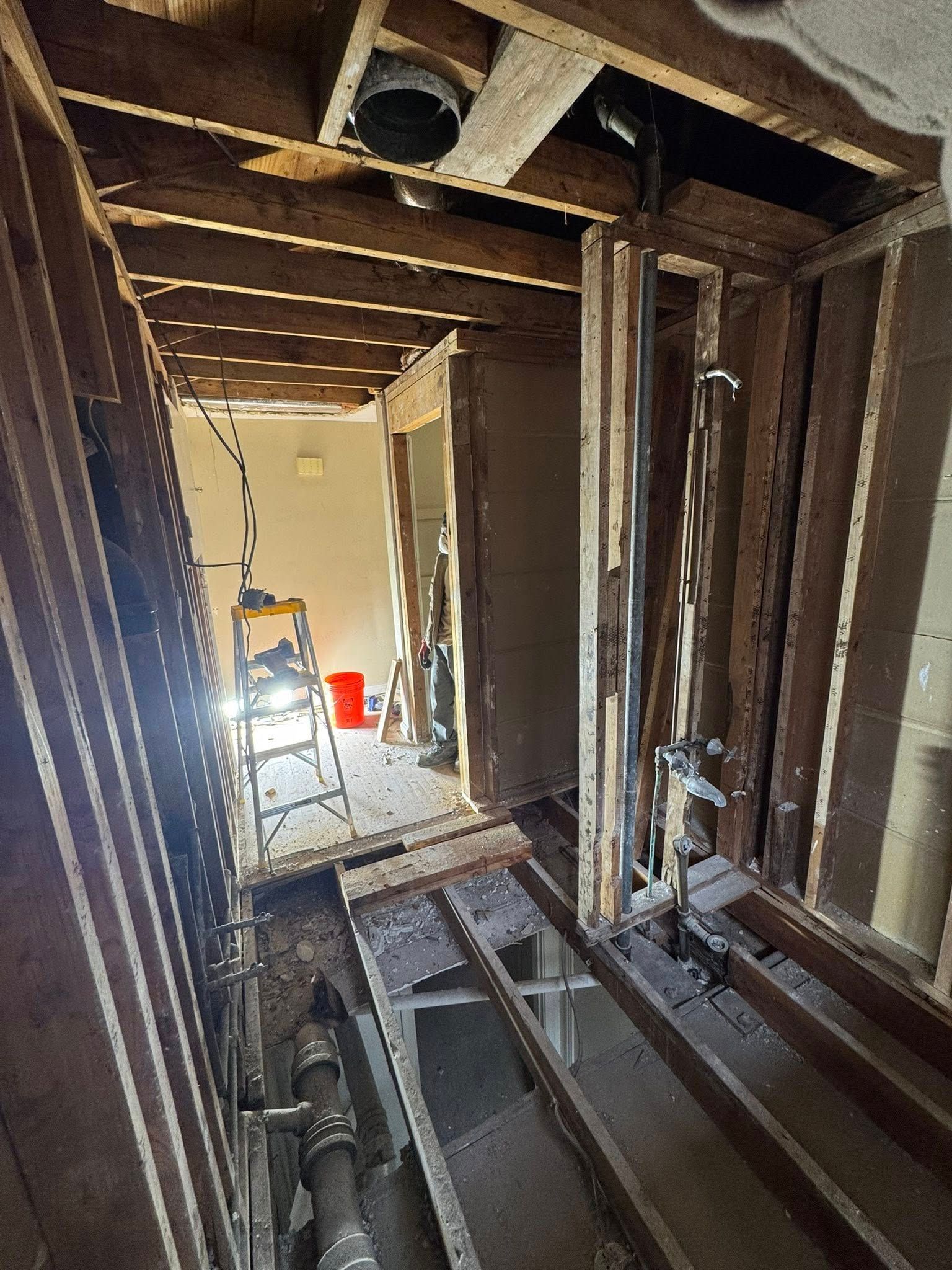 Bathroom remodel: Interior view showing exposed framing, plumbing, and a ladder inside.