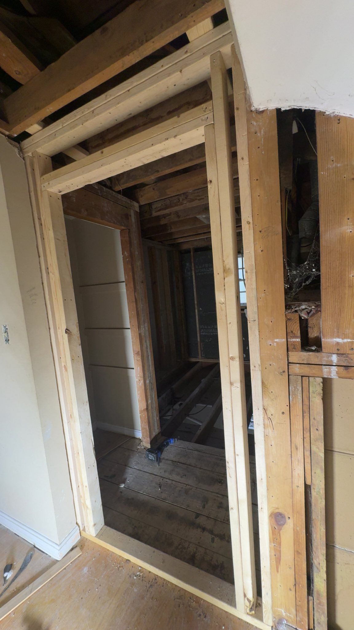 Framed doorway and hallway under construction, exposed studs, unfinished flooring, and drywall.