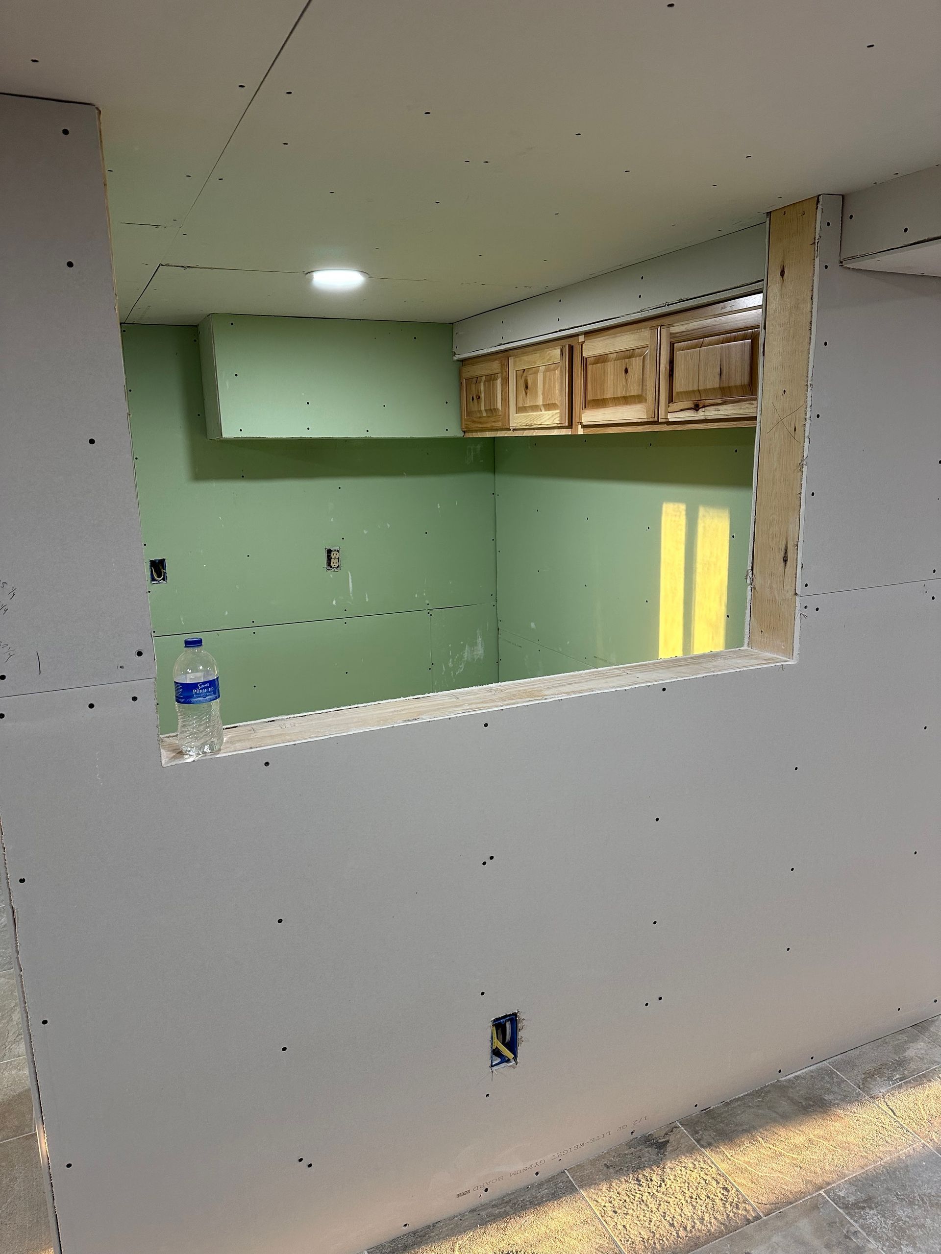 A kitchen under construction with a window in the wall.