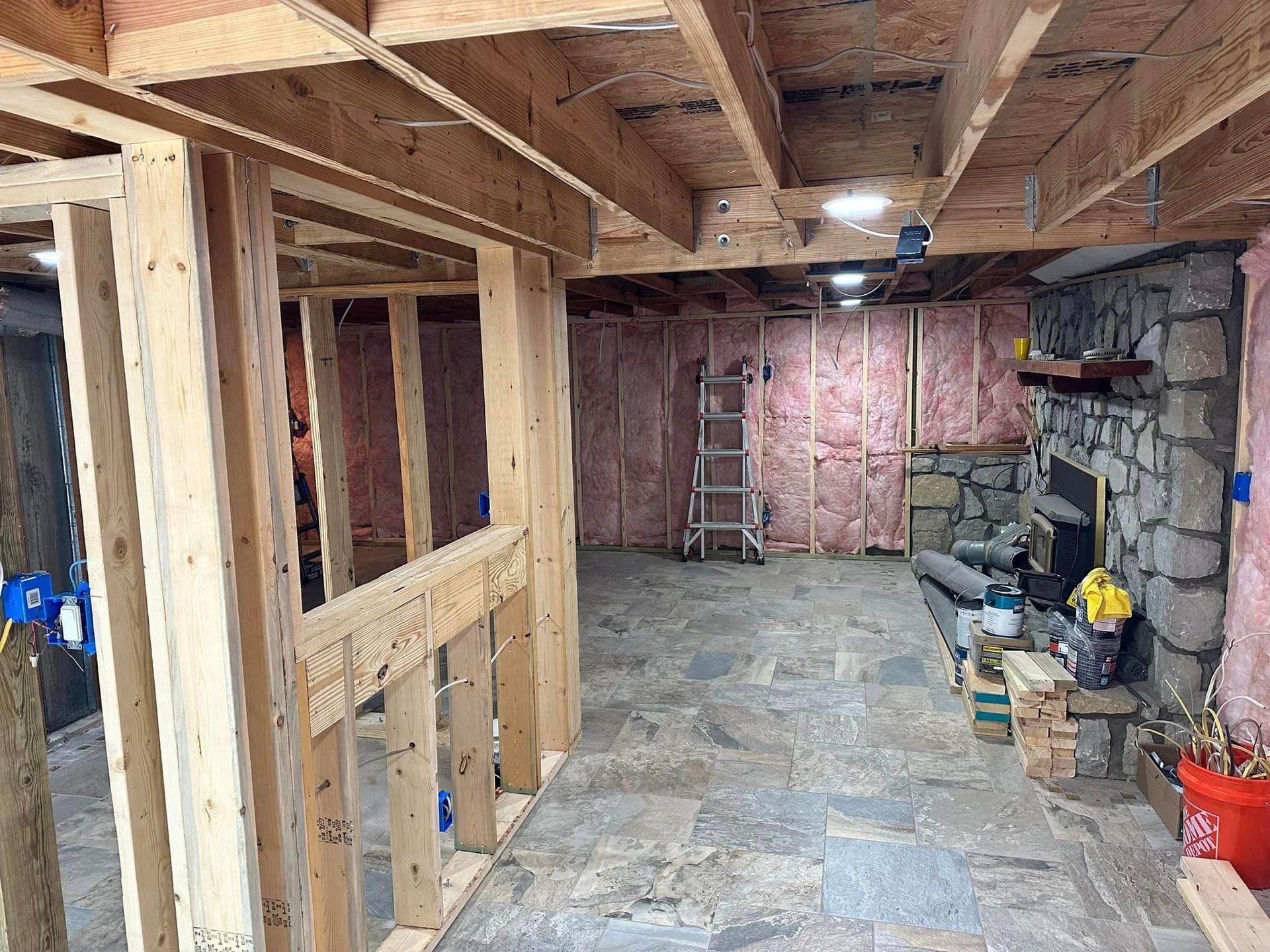 A basement under construction with a fireplace and a ladder.
