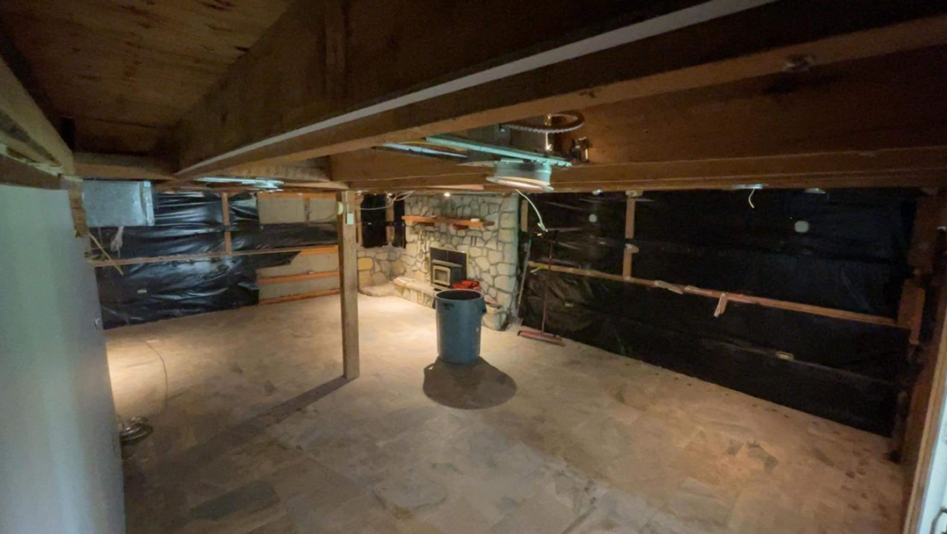A basement with a trash can in the middle of it.