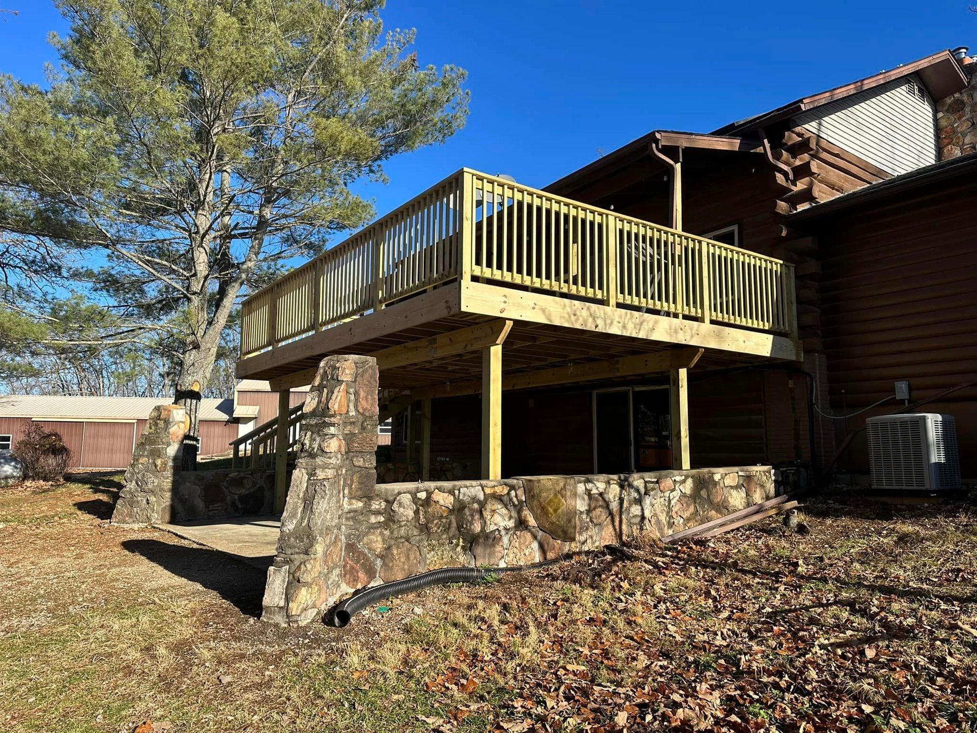 A large wooden deck is attached to the back of a house.