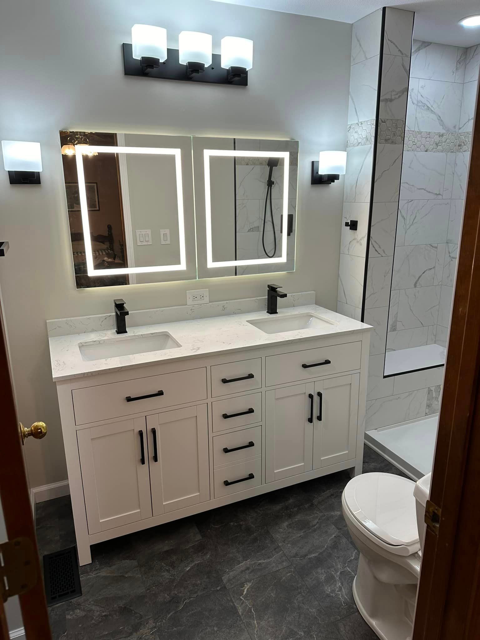 A bathroom with two sinks , a toilet , and a mirror.