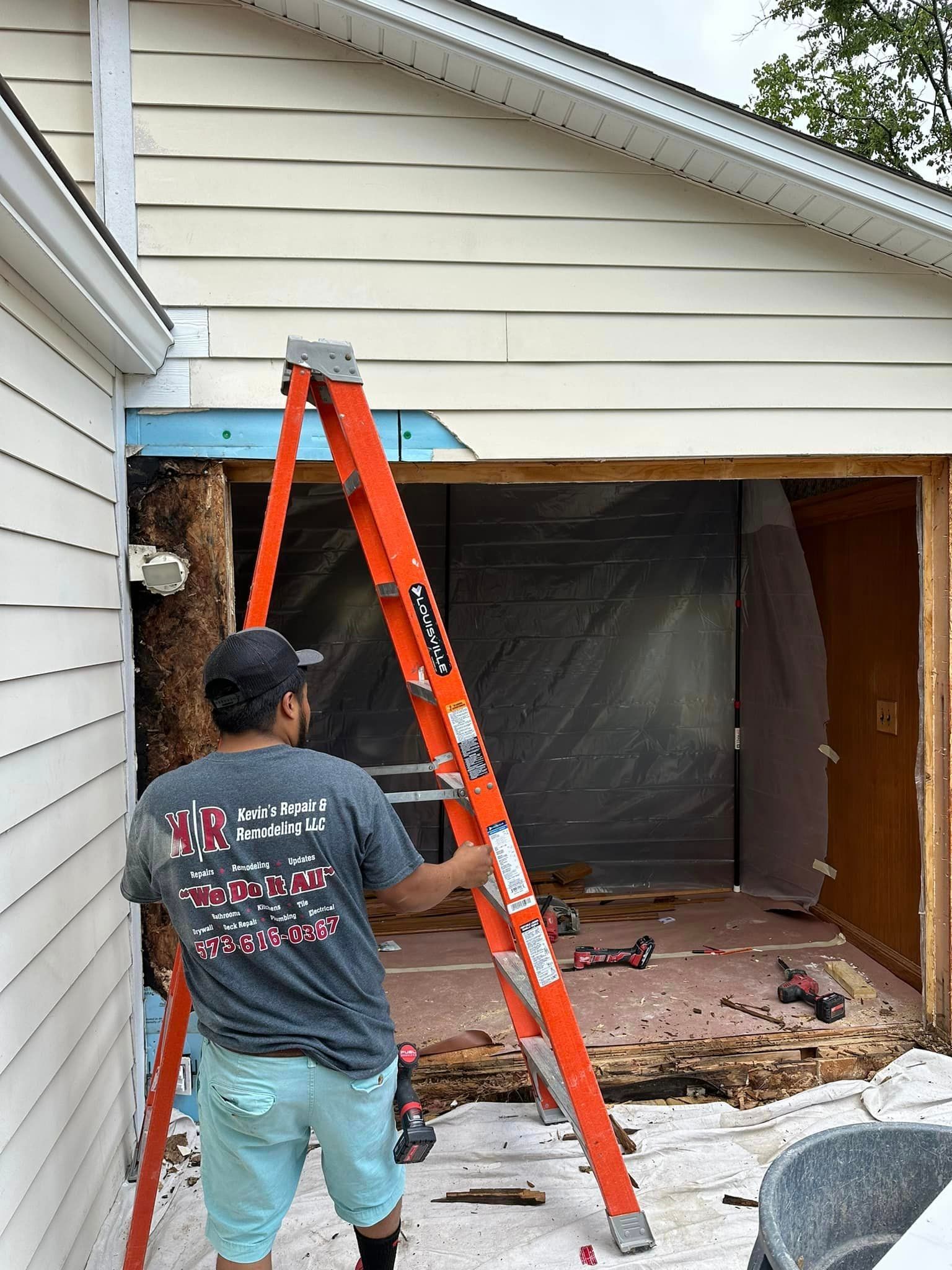 A man is standing on a ladder in front of a house.