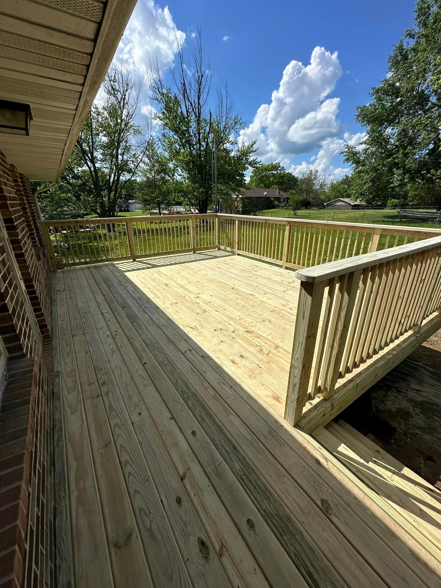 A wooden deck with a fence and stairs leading to it.