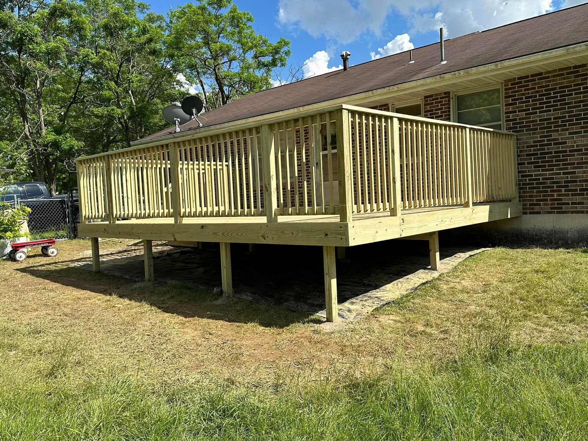 A wooden deck is sitting in front of a brick house.