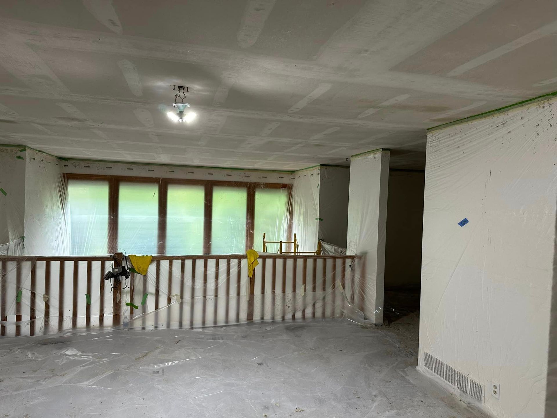 An empty room with a wooden railing and a ceiling fan.