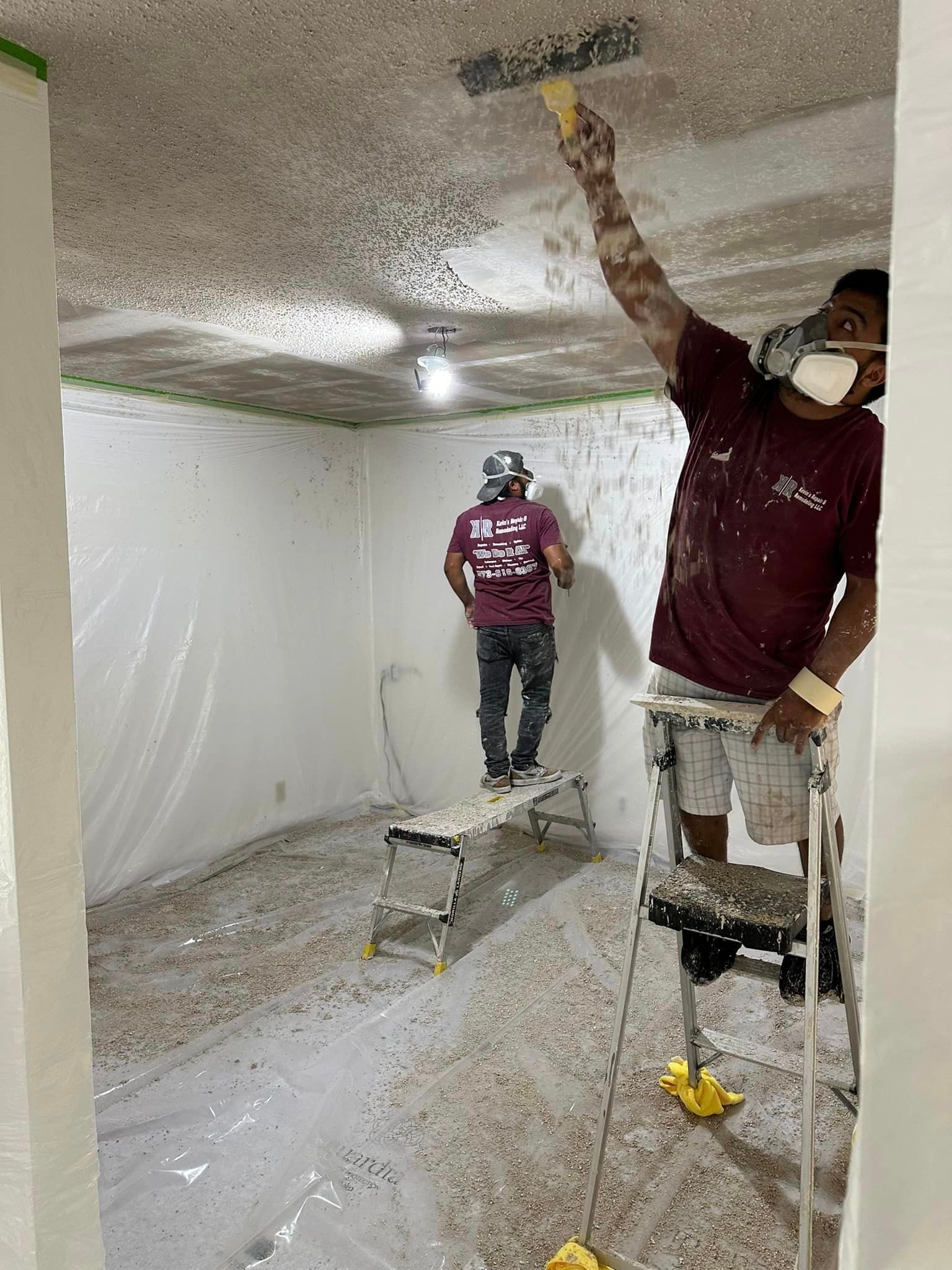 Two men are painting the ceiling of a room.