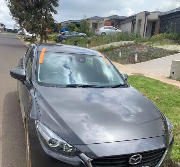 A mazda car is parked on the side of the road
