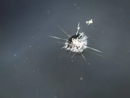 A close up of a broken windshield with a hole in it.