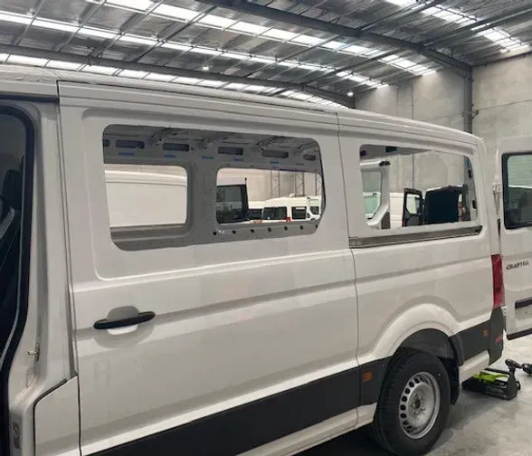 A white van is parked in a warehouse with the door open.
