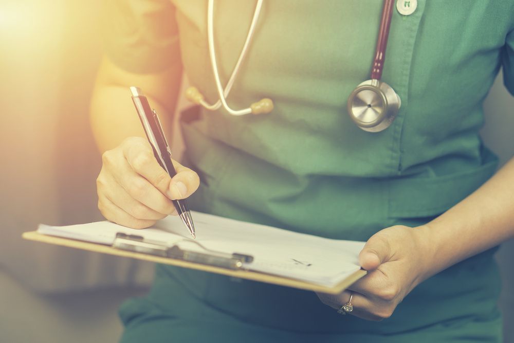 Nurse is Writing on a Clipboard With a Pen — Universal Nurse in Blackbutt North, QLD