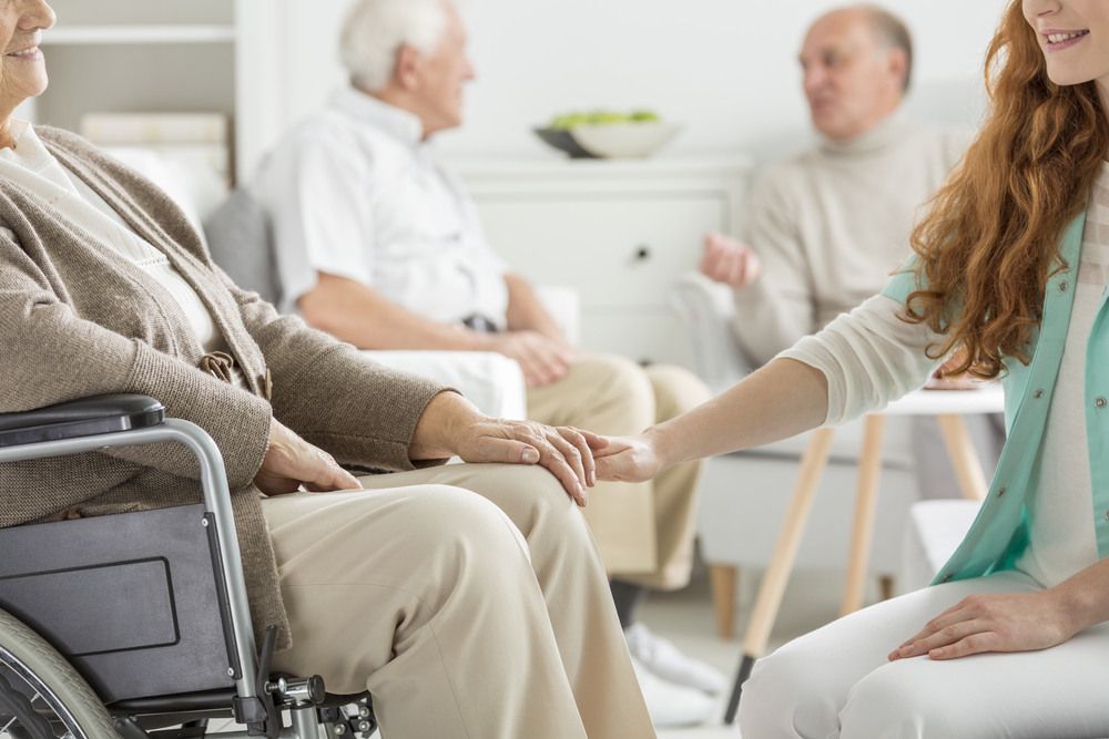 Woman is Holding the Hand of an Elderly Woman in a Wheelchair — Universal Nurse in Blackbutt North, QLD