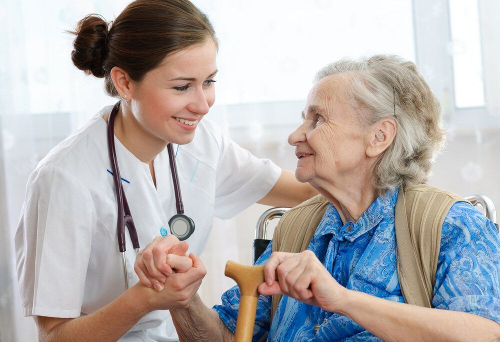 Nurse is Holding the Hand of an Elderly Woman in a Wheelchair — Universal Nurse in Blackbutt North, QLD