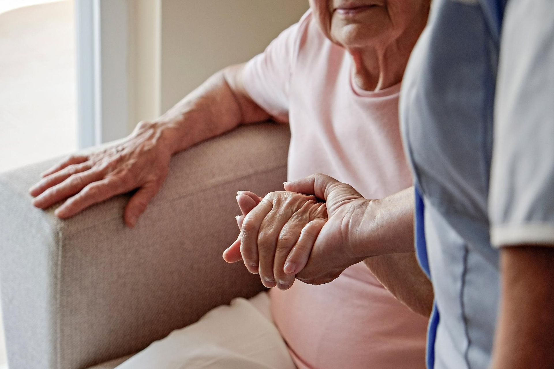 An Elderly Woman is Sitting on a Couch Holding a Nurse Hand — Universal Nurse in Blackbutt North, QLD