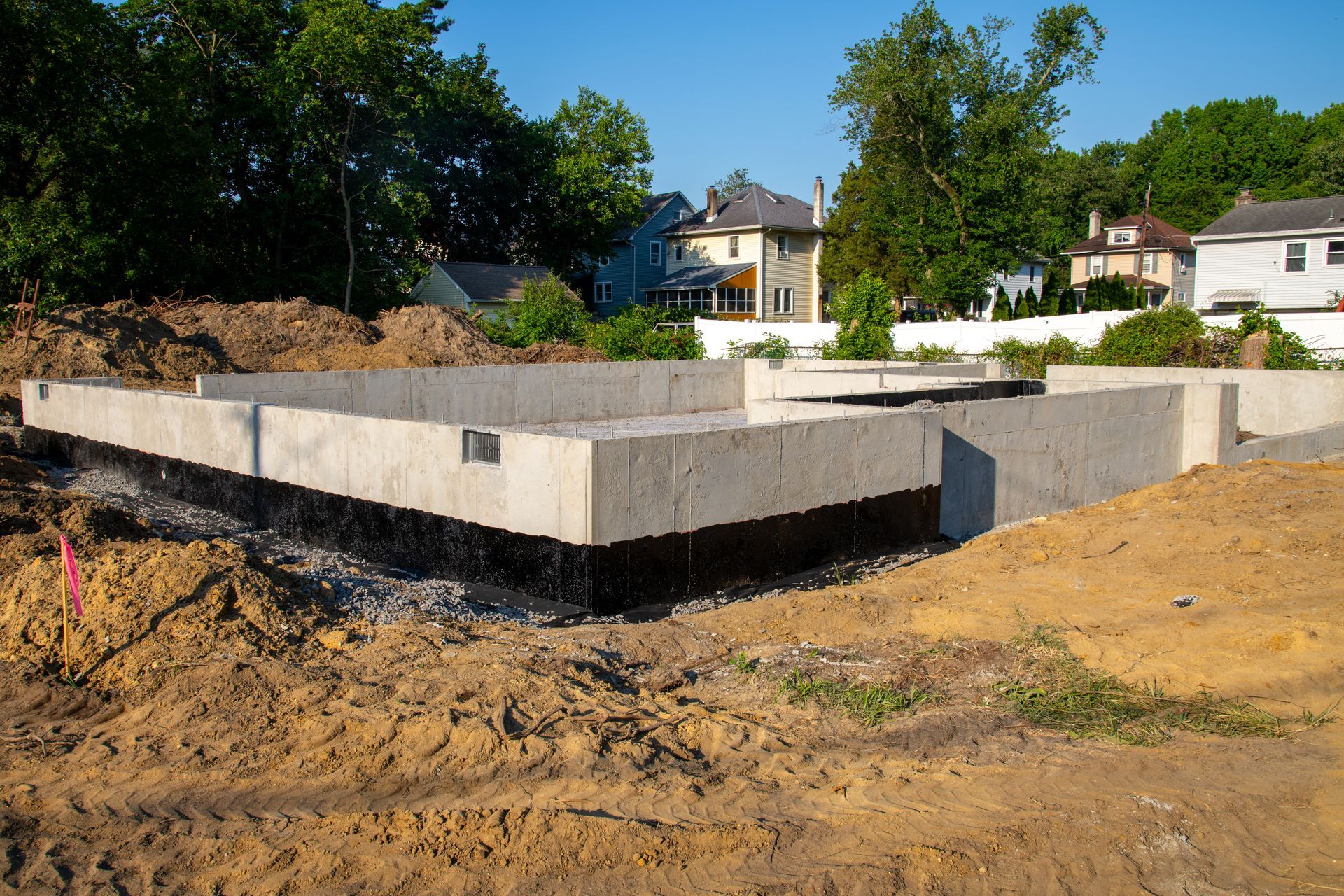 Fondation en béton pour un bâtiment en construction, avec revêtement étanche noir.