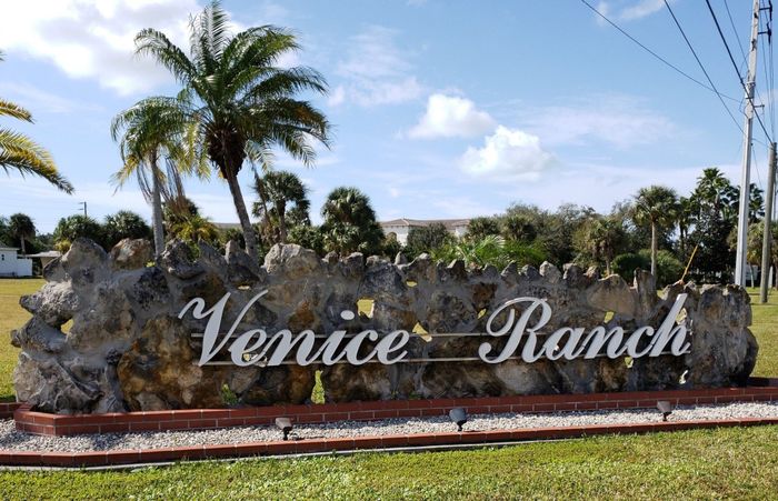a sign for venice ranch with palm trees in the background