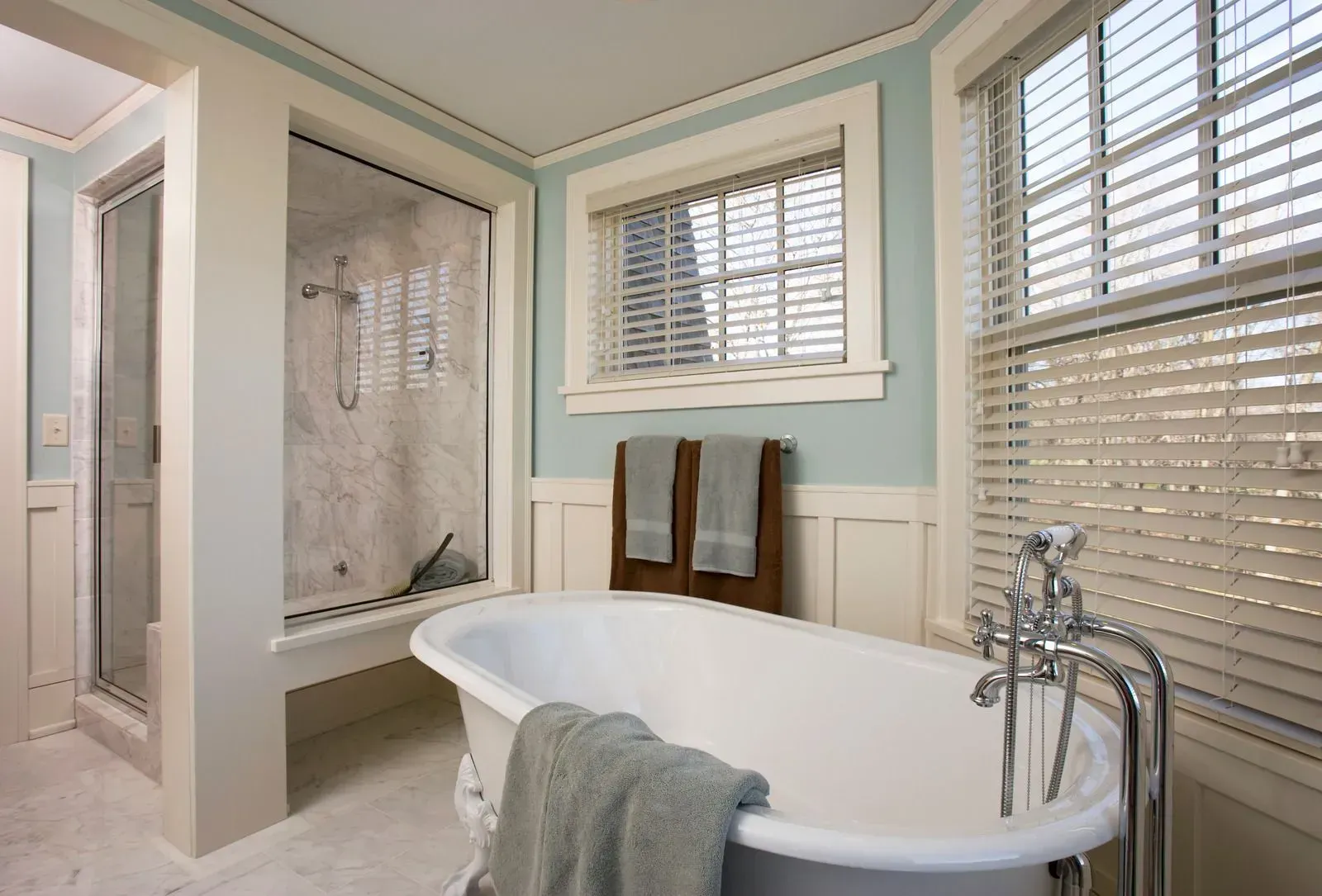 A bathroom with a tub , shower and window.