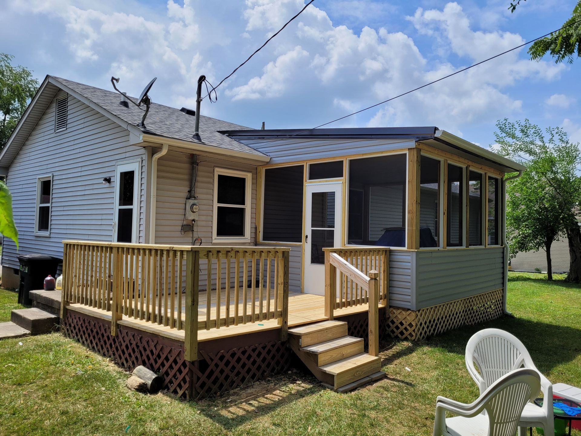 A house with a screened in porch and a wooden deck.