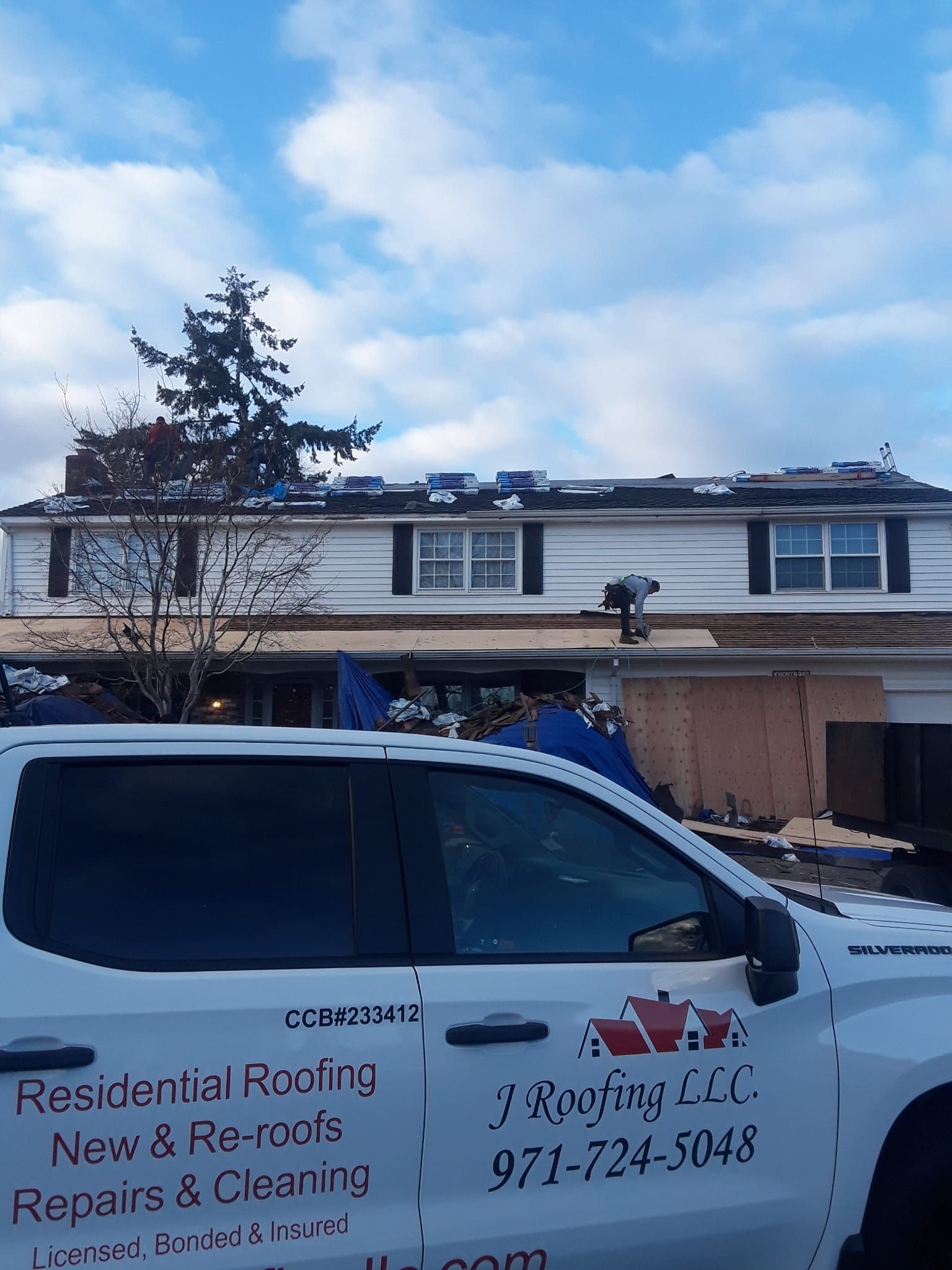 a residential roofing truck is parked in front of a house under construction .