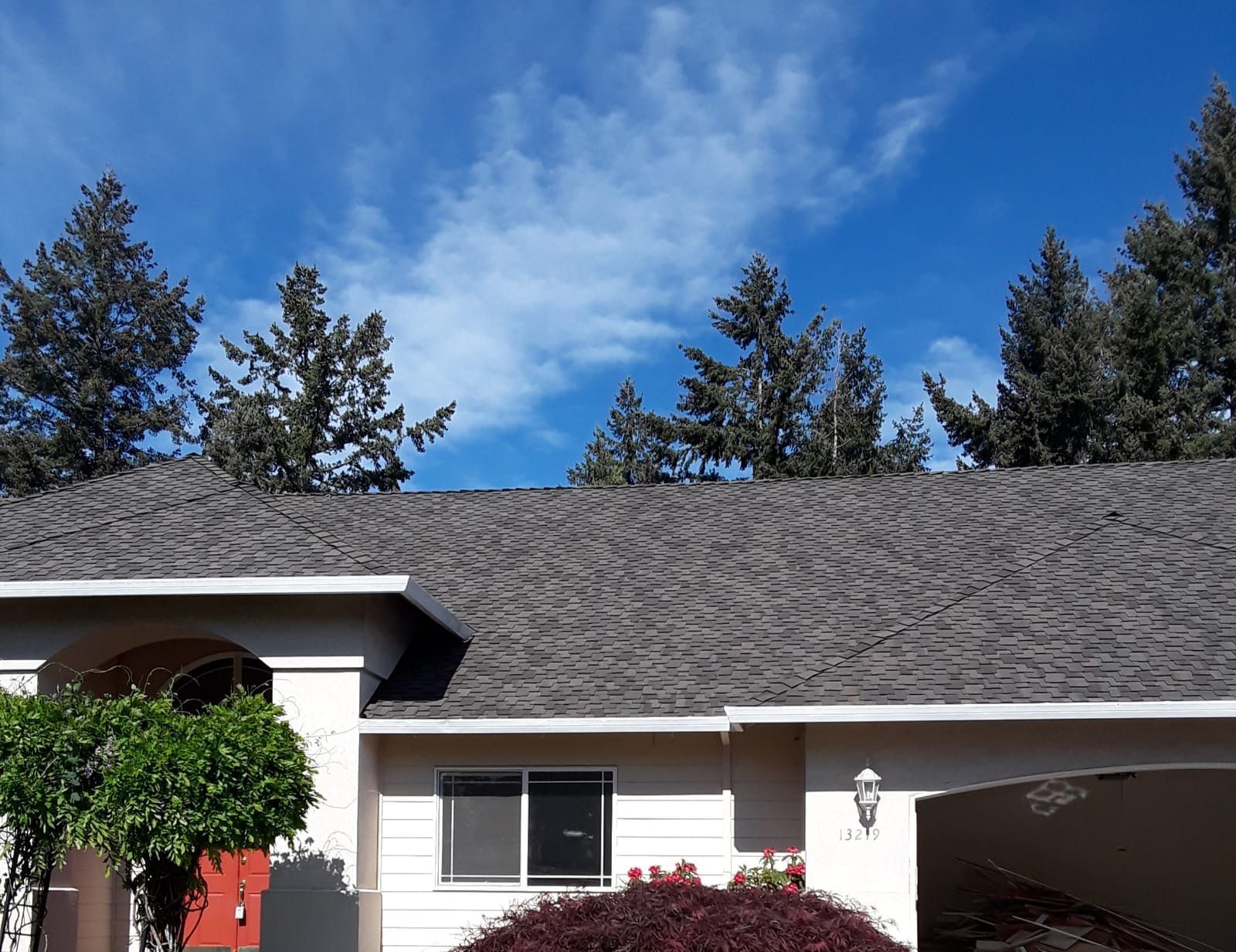 a house with a gray roof and trees in the background