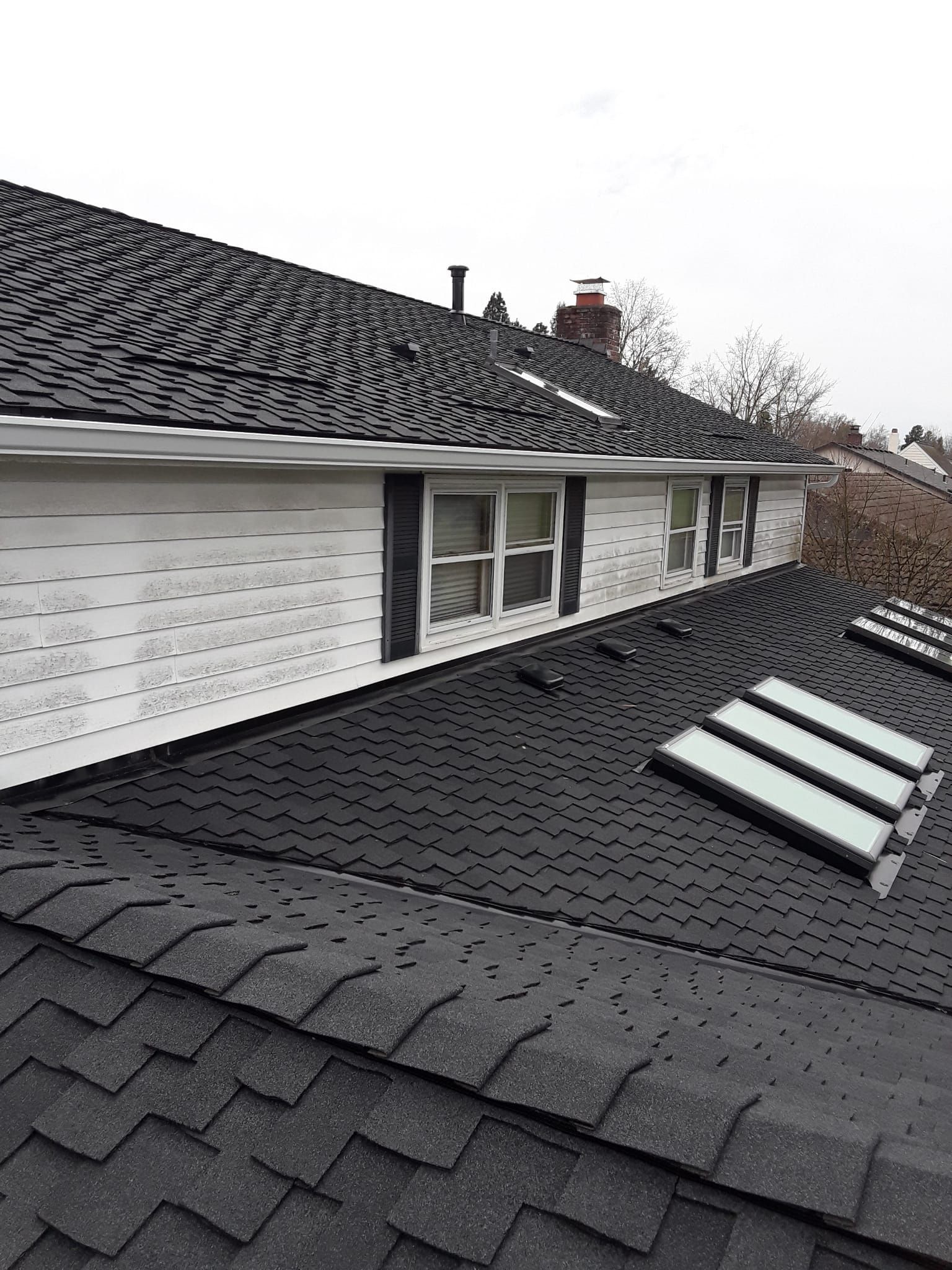 a house with a black roof and three skylights on it .