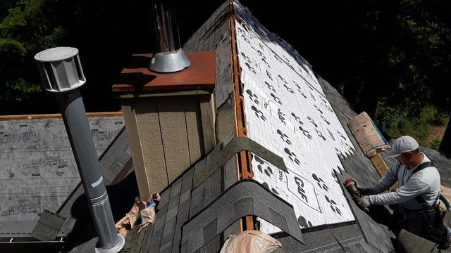 a man is working on the roof of a house .