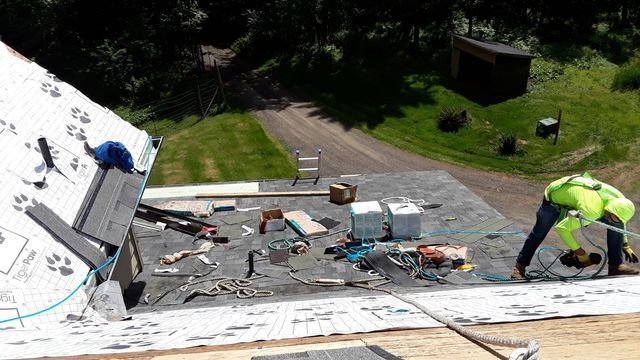 a man is working on the roof of a house .