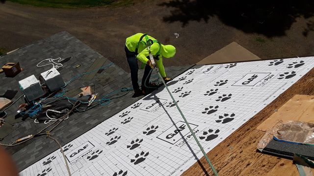 a man is working on the roof of a house .