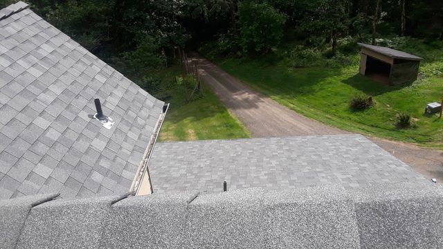 a view of a roof from the top of a house with a dirt road in the background .
