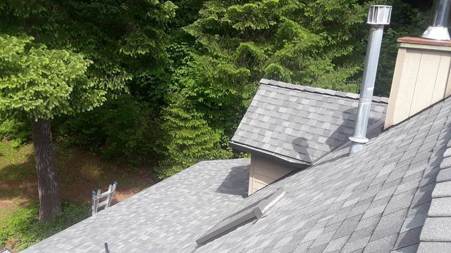 a roof with a chimney on it and trees in the background .