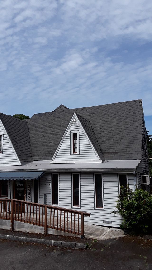 a white house with a gray roof and a ramp in front of it .