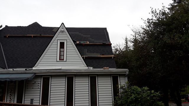 a white house with a black roof is surrounded by trees .