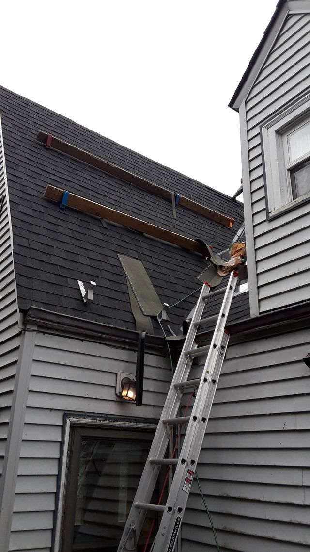 a person on a ladder is working on the roof of a house .