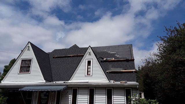 a white house with a black roof is being remodeled .