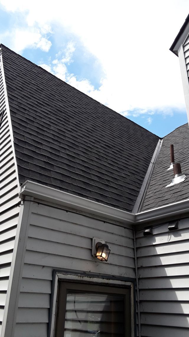 a house with a gray siding and a black roof .