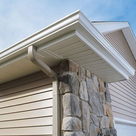 a house with a stone wall and a gutter on the side of it .