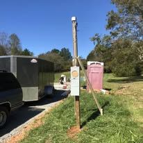A wooden pole is sitting in the grass next to a trailer.