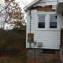 A white house with a lot of windows and a tree in the background.