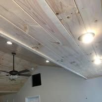 A living room with a wooden ceiling and a ceiling fan.