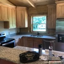 A kitchen with stainless steel appliances , granite counter tops , wooden cabinets and a window.