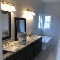 A bathroom with two sinks , two mirrors and a tub.