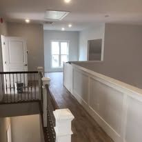 A hallway with a railing and stairs leading to the second floor of a house.